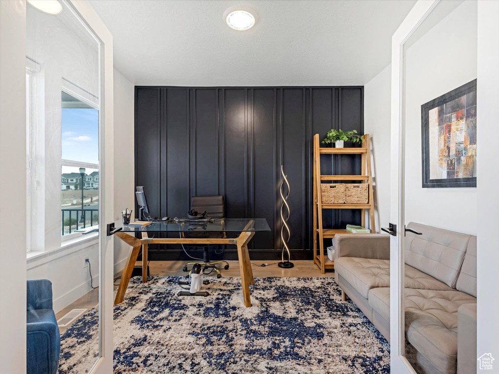 Office featuring a decorative wall and wood finished floors