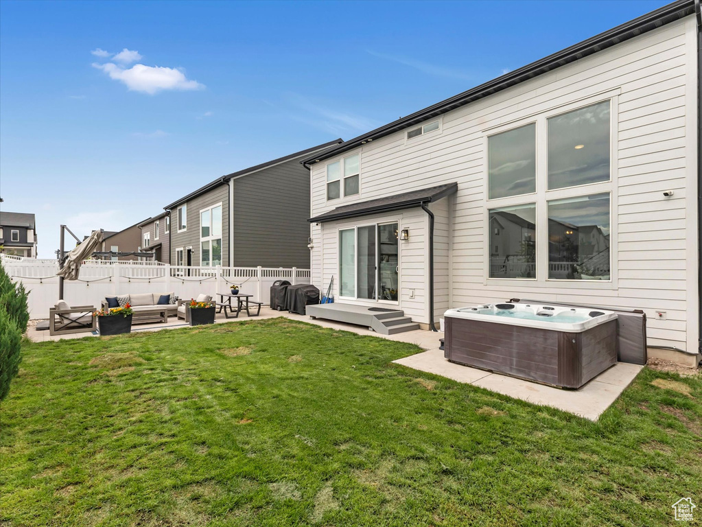 Back of house with a hot tub, an outdoor living space, and a patio