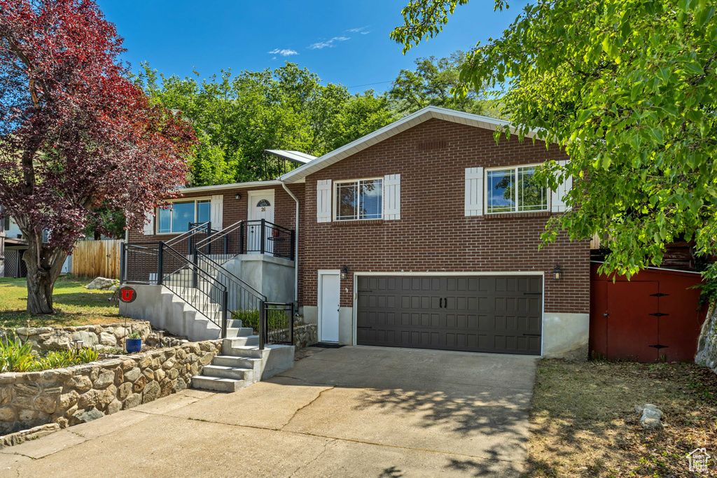 View of front facade with a garage, driveway, and brick siding
