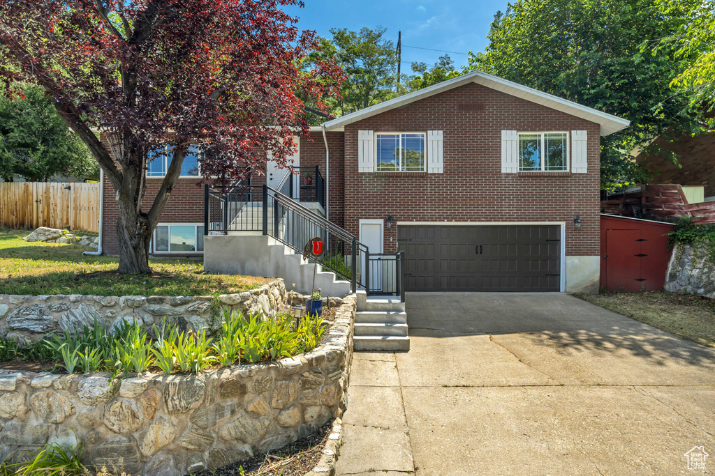 View of front of property with an attached garage, concrete driveway, and brick siding