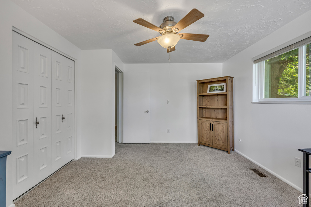 Unfurnished bedroom featuring carpet floors, a closet, ceiling fan, and a textured ceiling
