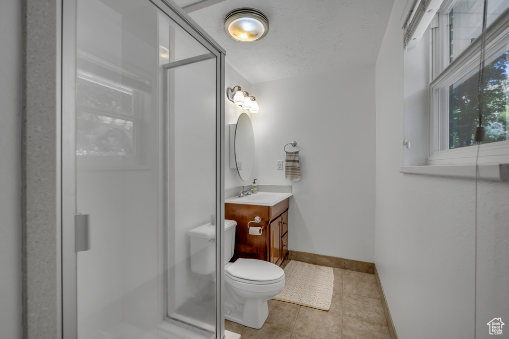Full bath featuring vanity, a shower stall, tile patterned flooring, and a textured ceiling