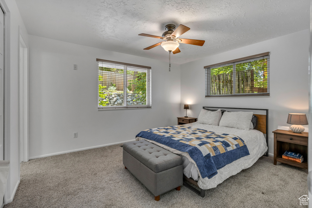 Bedroom with multiple windows, carpet flooring, a textured ceiling, and ceiling fan