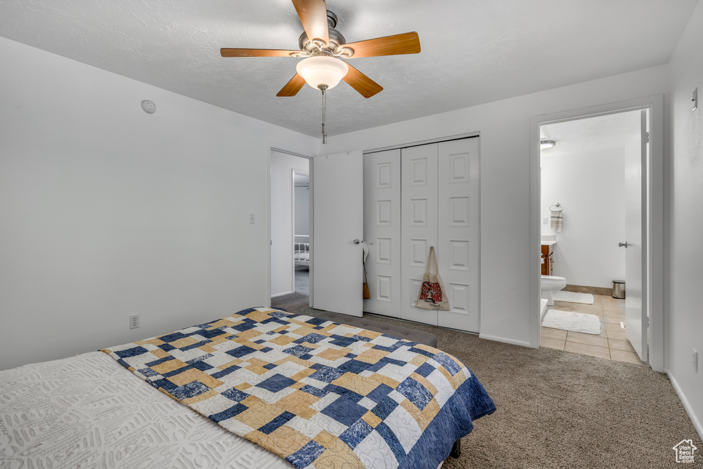 Tiled bedroom featuring a closet, carpet, ceiling fan, and ensuite bath