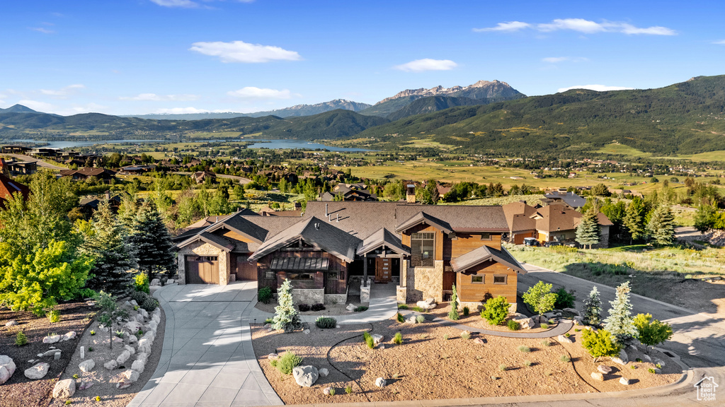 View of front of property with a mountain view, stone siding, and driveway
