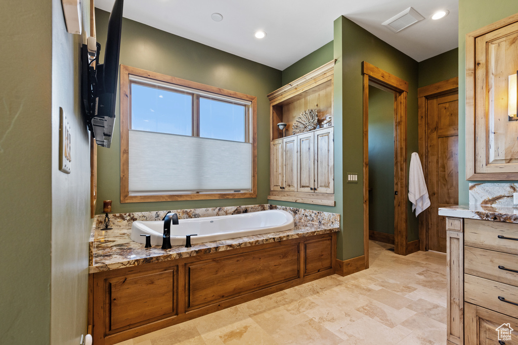 Full bathroom featuring a garden tub and baseboards