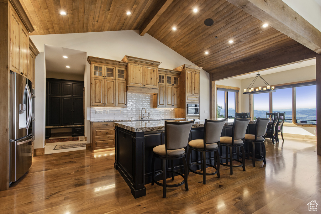 Kitchen with stainless steel appliances, a large island with sink, dark wood-style floors, decorative backsplash, and recessed lighting