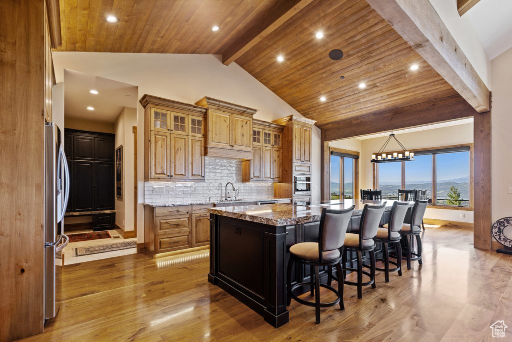 Kitchen with a kitchen island, freestanding refrigerator, recessed lighting, a kitchen breakfast bar, and decorative backsplash