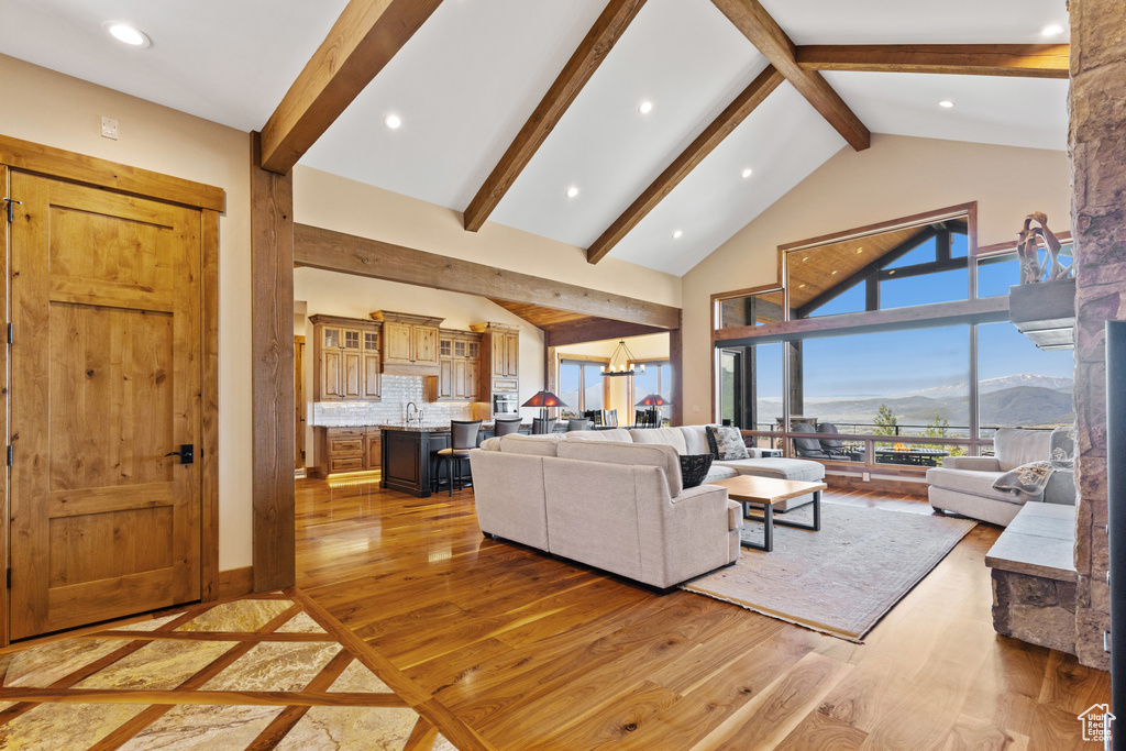 Living room featuring beam ceiling, light wood finished floors, high vaulted ceiling, recessed lighting, and a mountain view