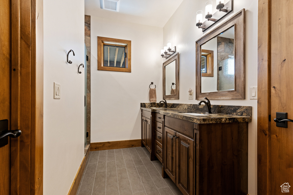 Bathroom with double vanity, tile patterned floors, and an enclosed shower