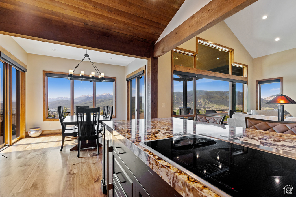 Kitchen with lofted ceiling, a mountain view, black electric stovetop, a chandelier, and light wood-style flooring
