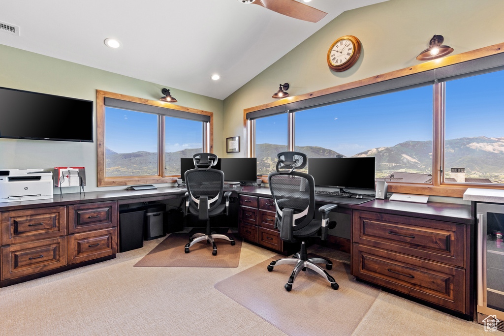 Office space featuring lofted ceiling, beverage cooler, light colored carpet, recessed lighting, and built in desk