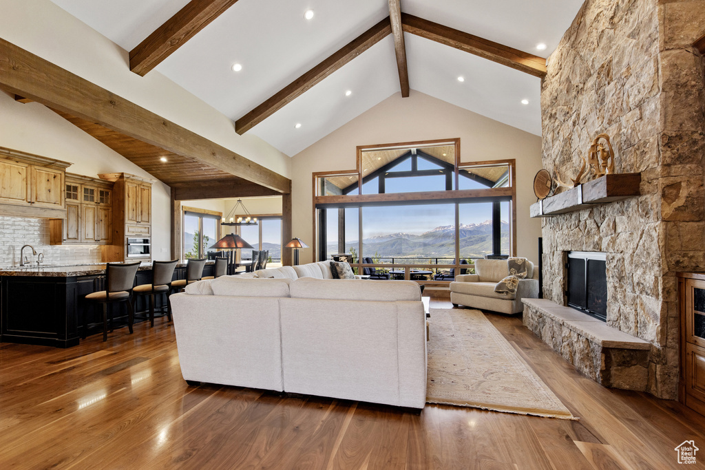 Living area with a stone fireplace, beamed ceiling, high vaulted ceiling, wood finished floors, and a mountain view