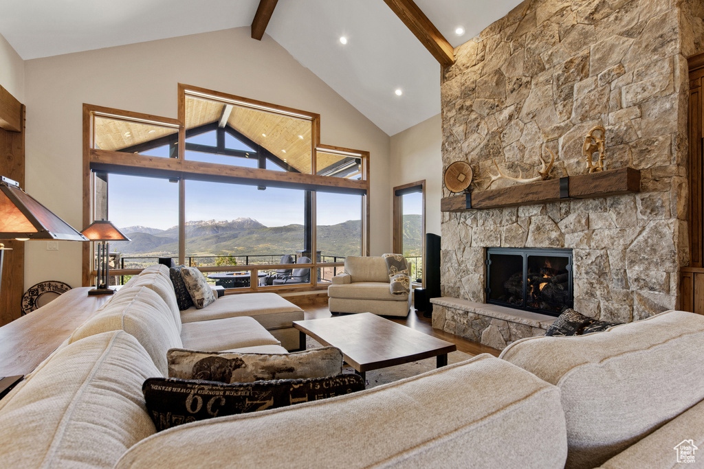 Living room featuring beamed ceiling, a mountain view, a stone fireplace, high vaulted ceiling, and wood finished floors