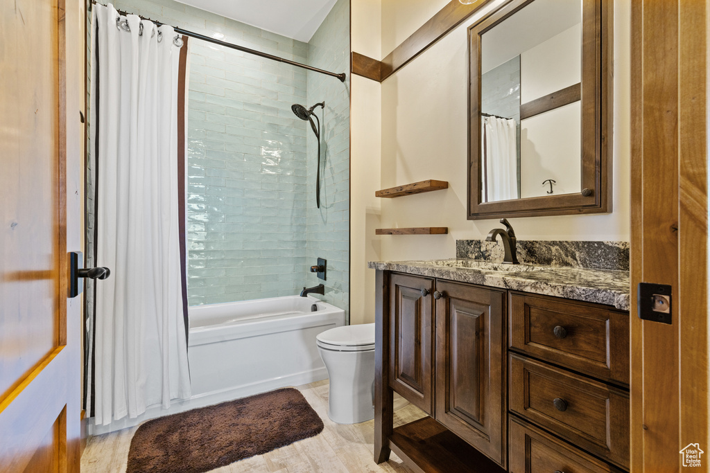 Full bath with vanity, shower / tub combo with curtain, and wood finished floors