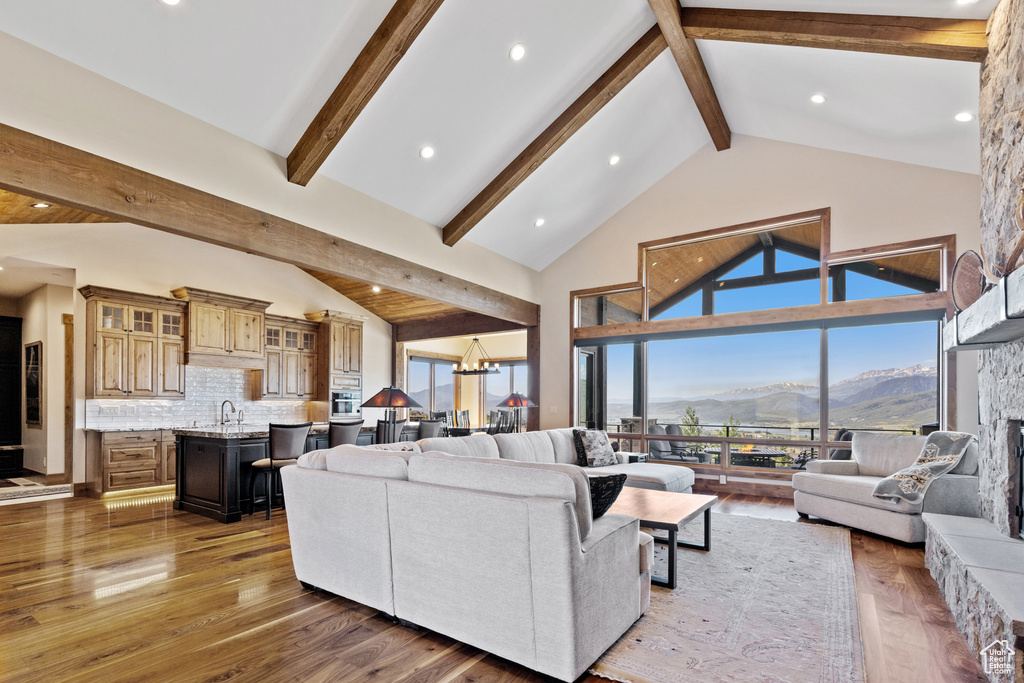 Living room featuring a mountain view, beamed ceiling, a chandelier, wood finished floors, and high vaulted ceiling
