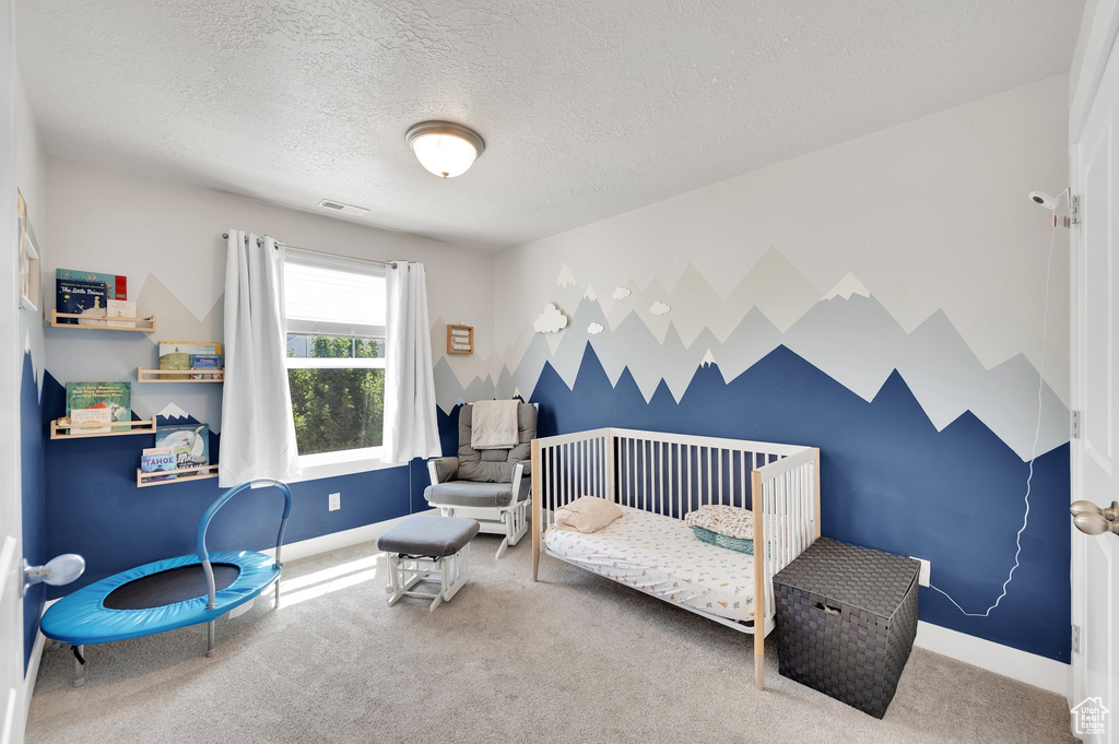 Bedroom featuring carpet floors, a textured ceiling, and a crib