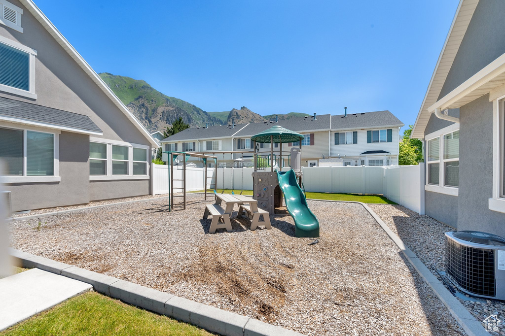 View of jungle gym with a mountain view, a fenced backyard, and a residential view