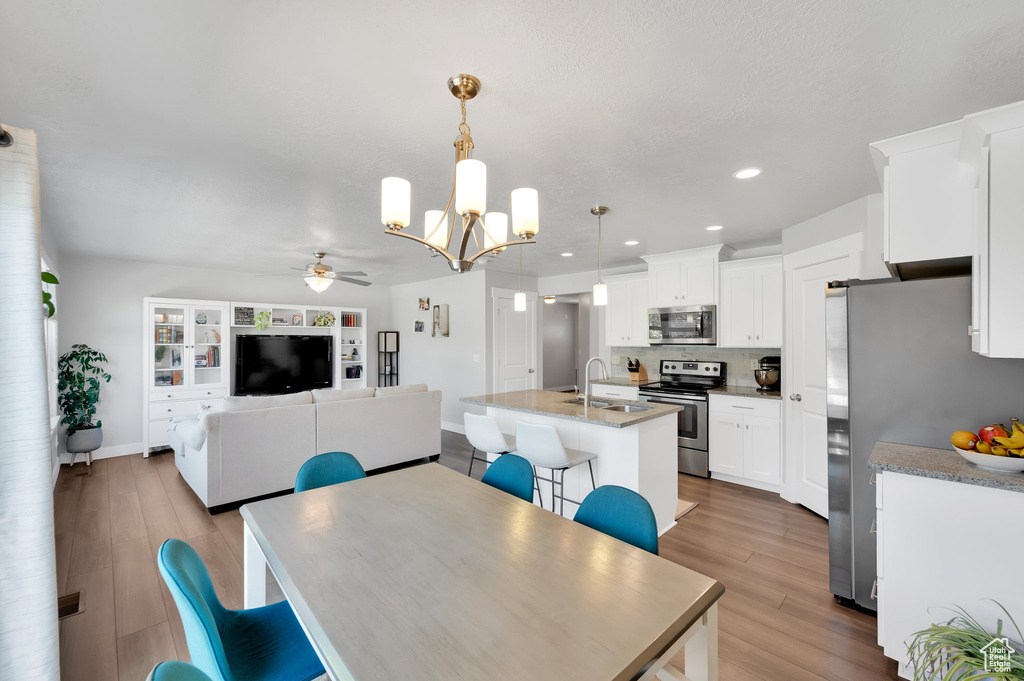 Dining area featuring ceiling fan, a chandelier, wood finished floors, and recessed lighting