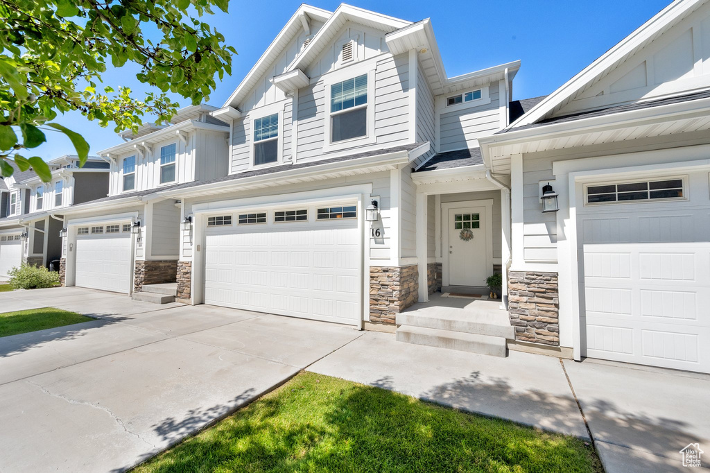 View of front of home with board and batten siding, stone siding, concrete driveway, and a garage