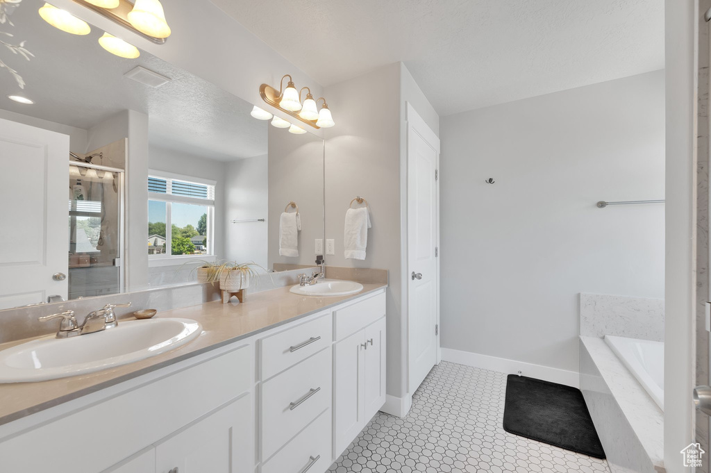 Bathroom featuring double vanity, a bath, and a shower stall