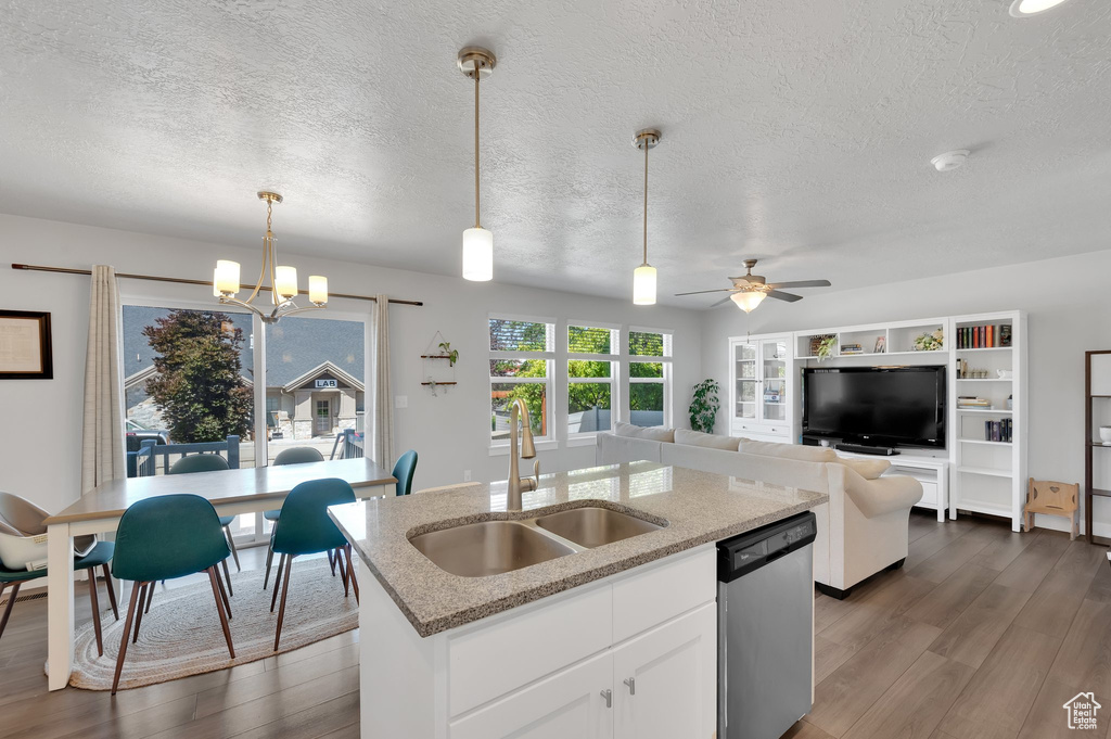 Kitchen featuring stainless steel dishwasher, dark wood-style flooring, a textured ceiling, pendant lighting, and white cabinetry