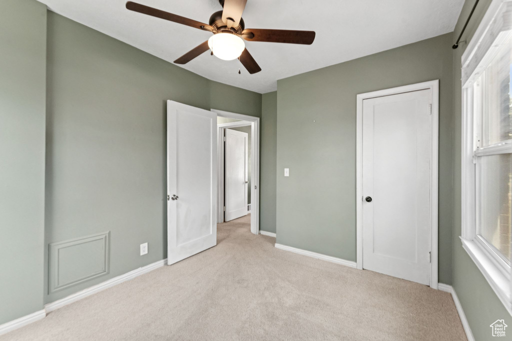 Unfurnished bedroom featuring light carpet, a closet, and ceiling fan