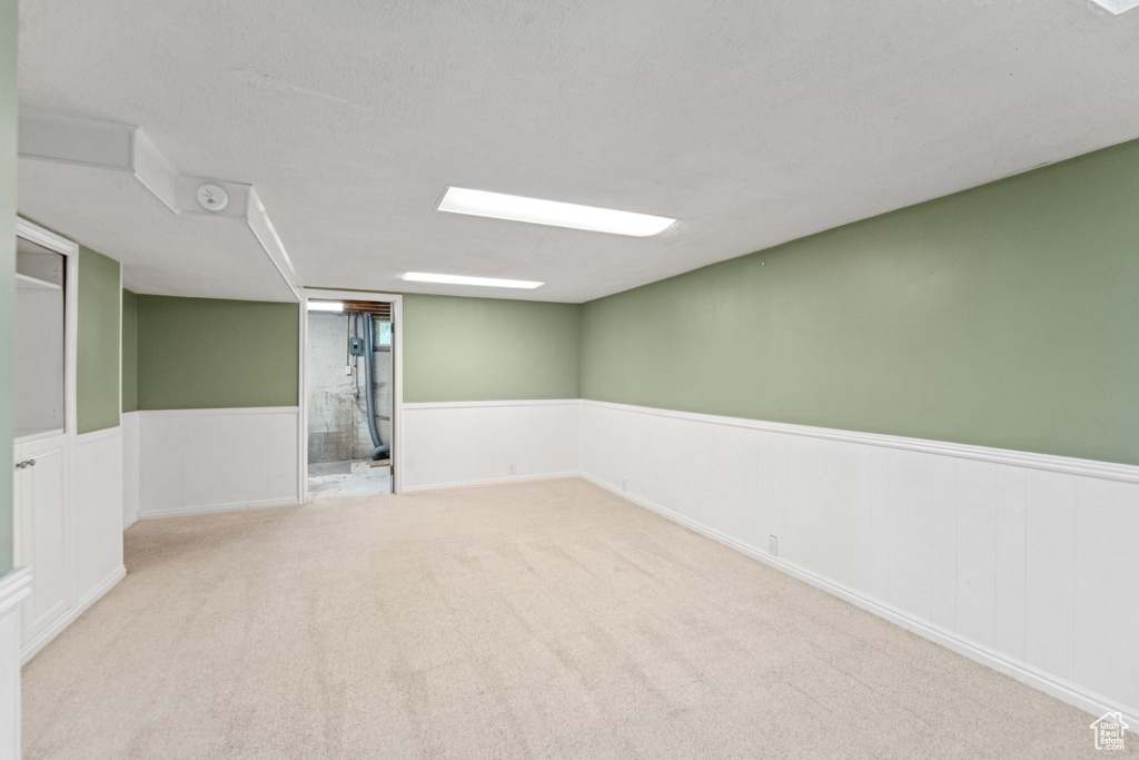 Carpeted empty room featuring a wainscoted wall