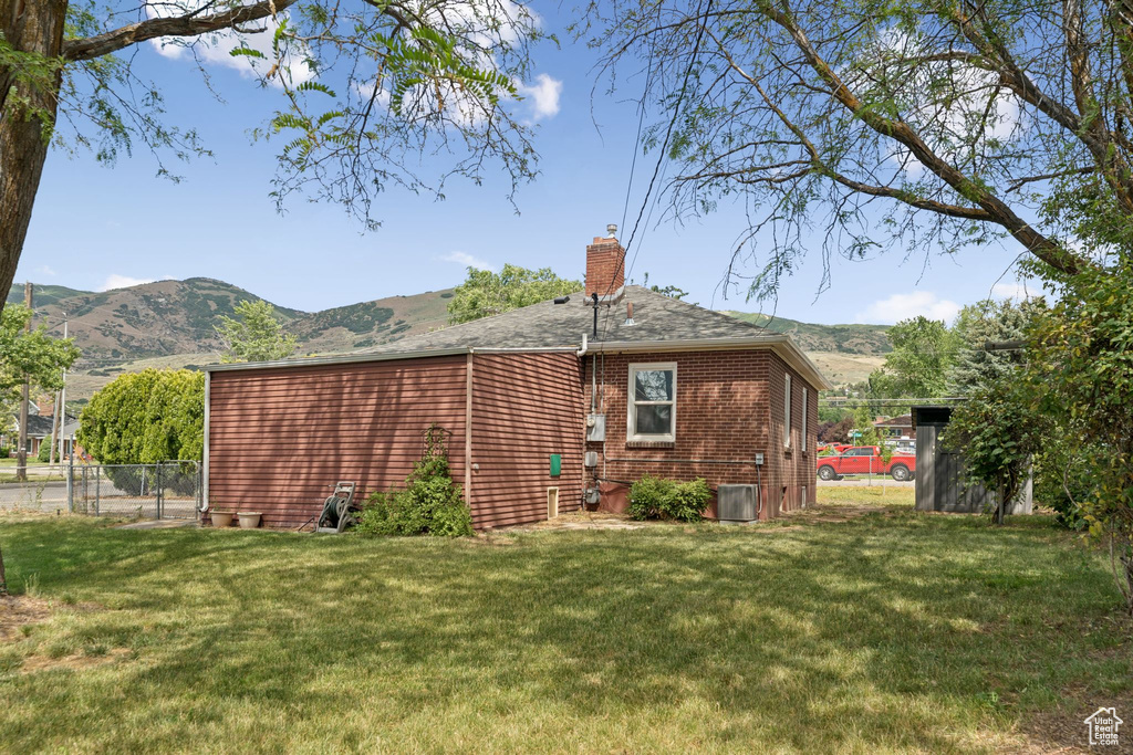 Back of house with a chimney, a mountain view, and brick siding