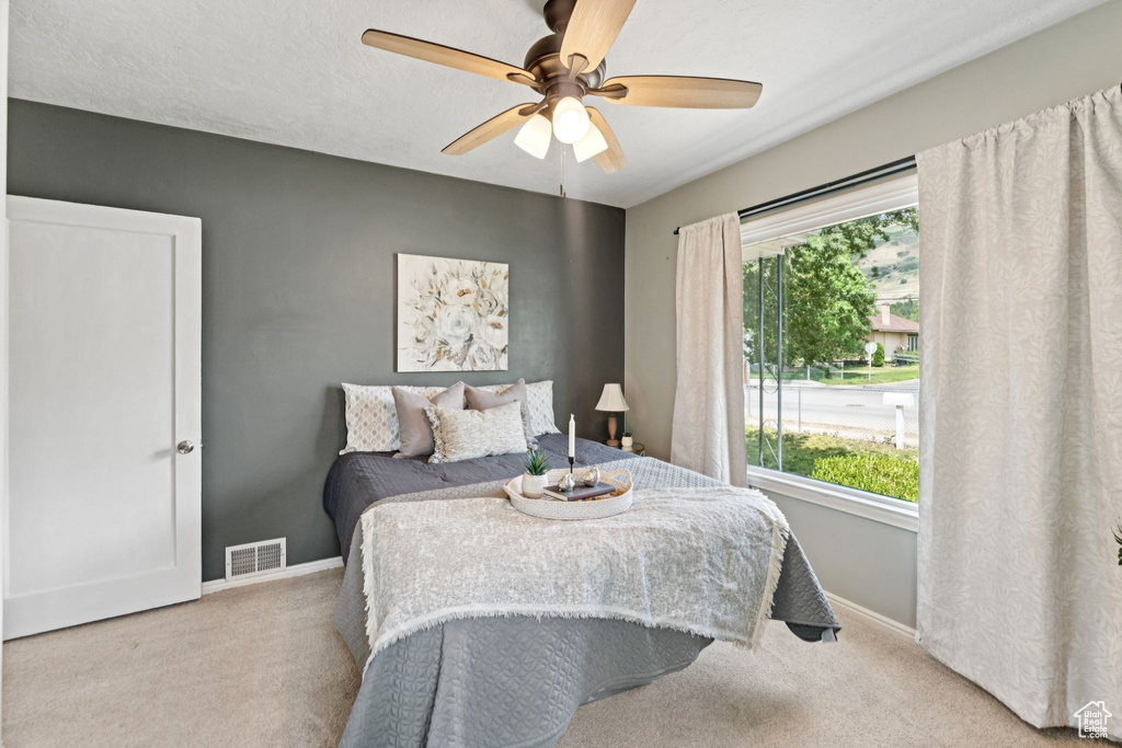 Bedroom featuring carpet flooring, multiple windows, and ceiling fan
