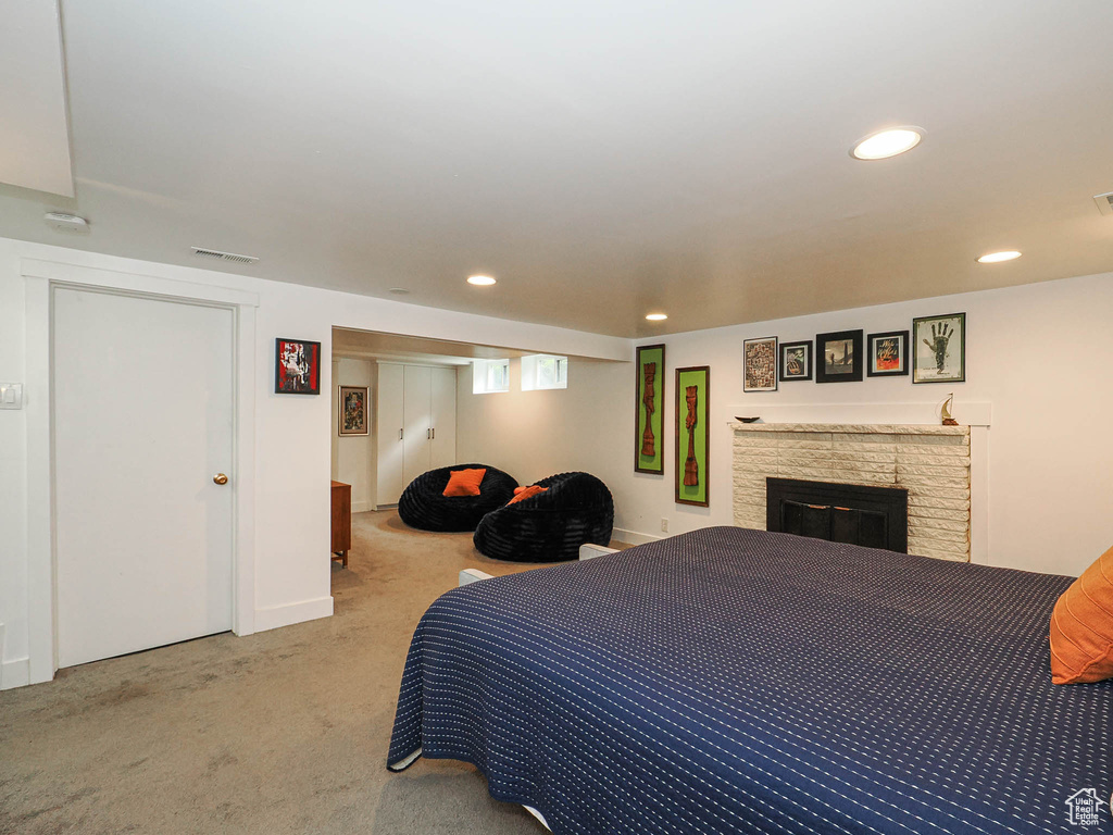 Carpeted bedroom with recessed lighting and a stone fireplace
