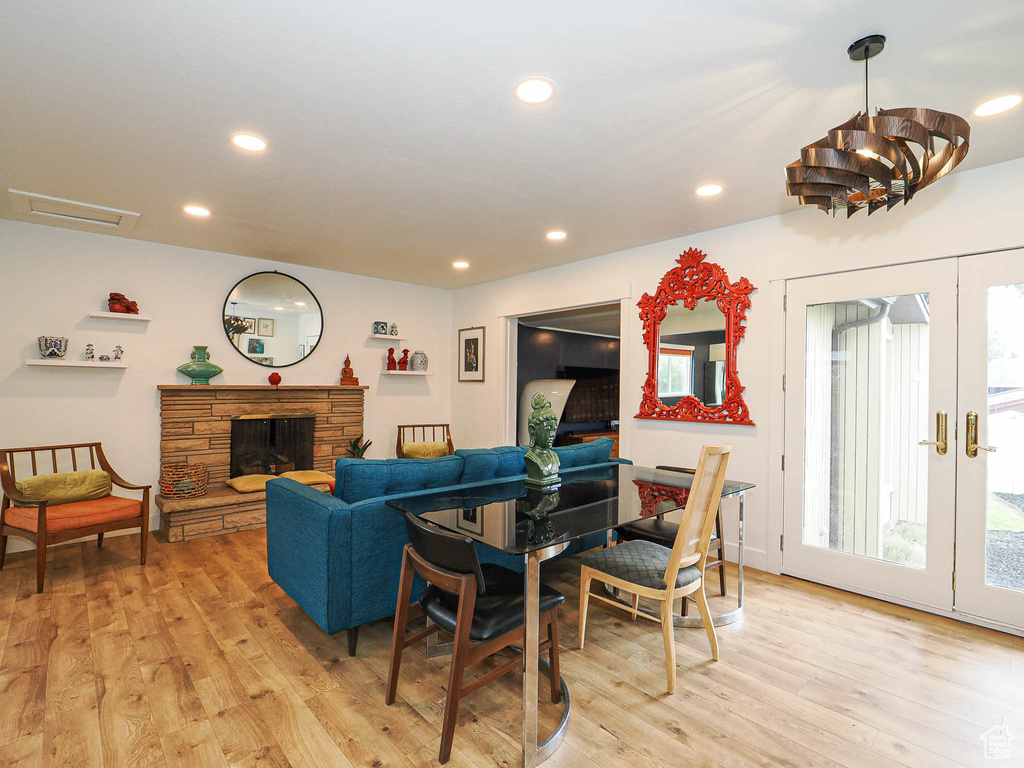 Living room with light wood finished floors, recessed lighting, a fireplace, and a chandelier