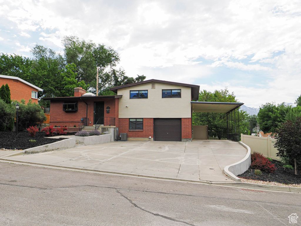 Tri-level home featuring brick siding, an attached garage, driveway, and a chimney