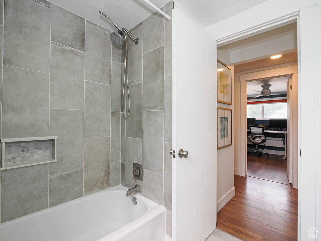 Bathroom with hardwood / wood-style floors, bathing tub / shower combination, and ceiling fan
