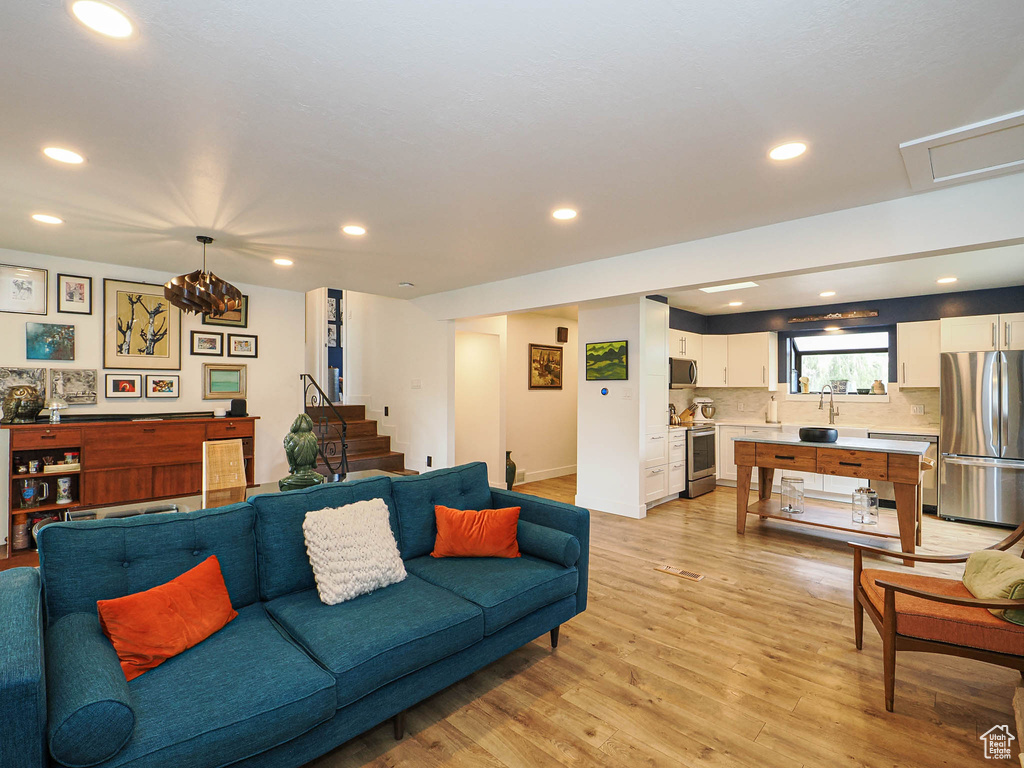 Living room featuring light wood-type flooring, recessed lighting, and stairway