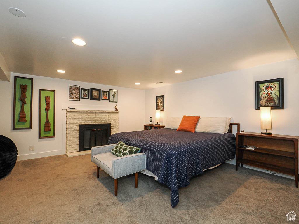 Carpeted bedroom with recessed lighting and a glass covered fireplace