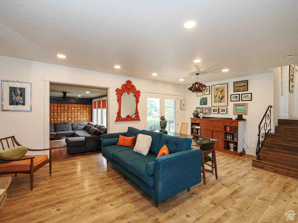 Living room with stairs, light wood-style flooring, recessed lighting, and a chandelier
