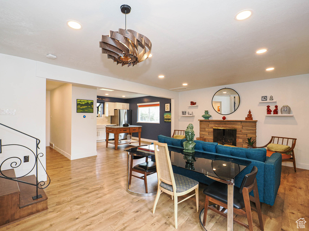 Dining area with recessed lighting, light wood-type flooring, a stone fireplace, and stairs