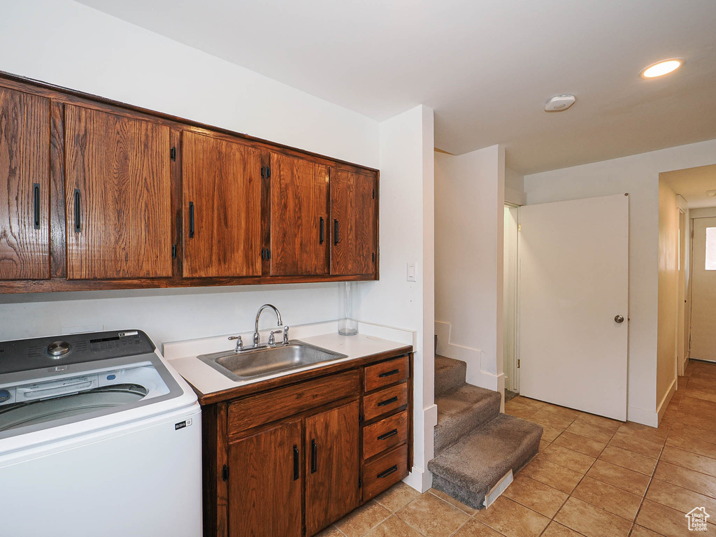 Laundry room featuring washer / dryer, cabinet space, and light tile patterned floors
