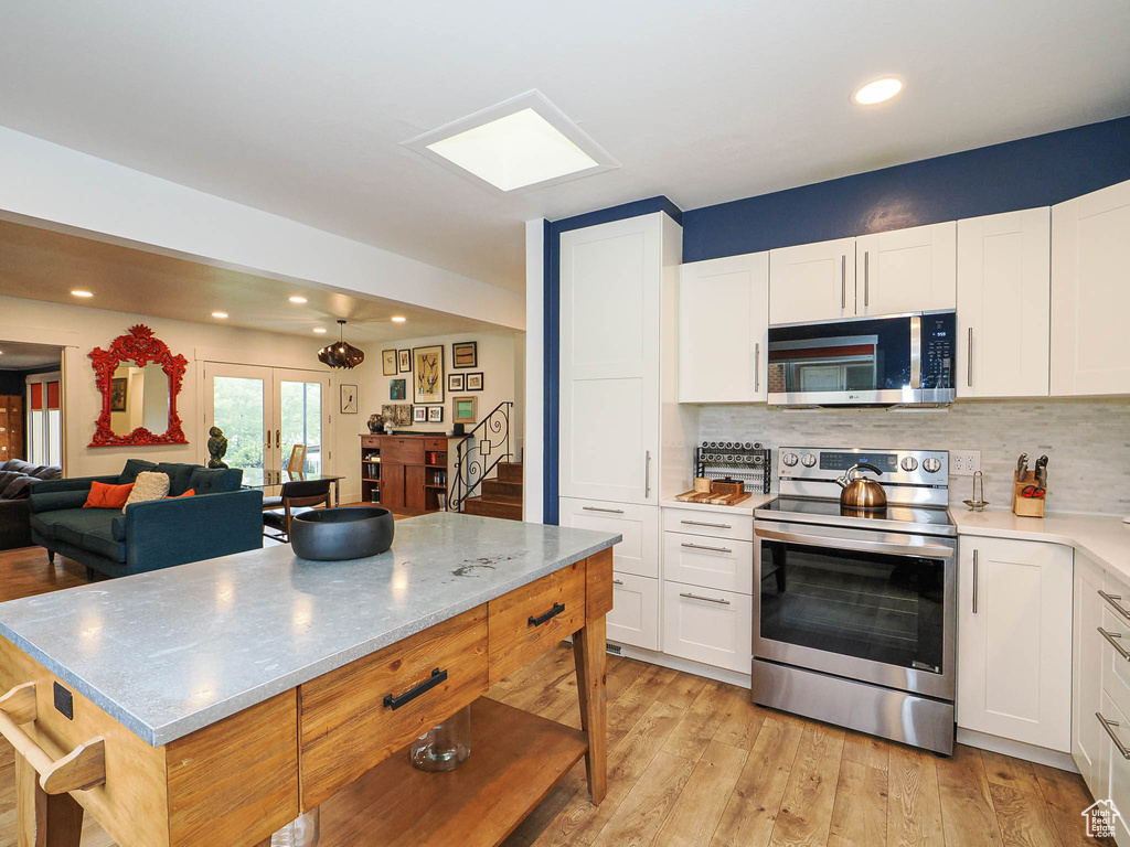 Kitchen with stainless steel appliances, white cabinetry, backsplash, and recessed lighting