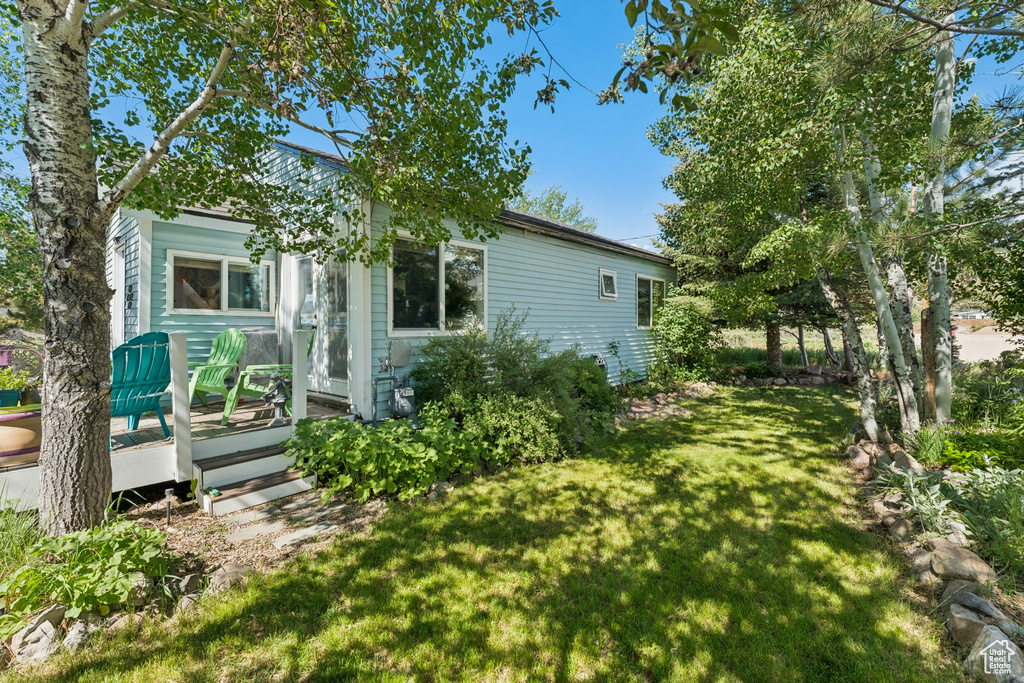 View of side of property with a yard and a wooden deck