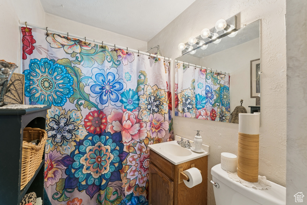 Bathroom with vanity, a textured wall, and a shower with shower curtain