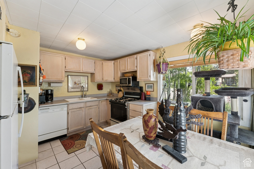 Kitchen featuring white appliances, light brown cabinetry, light countertops, and light tile patterned flooring