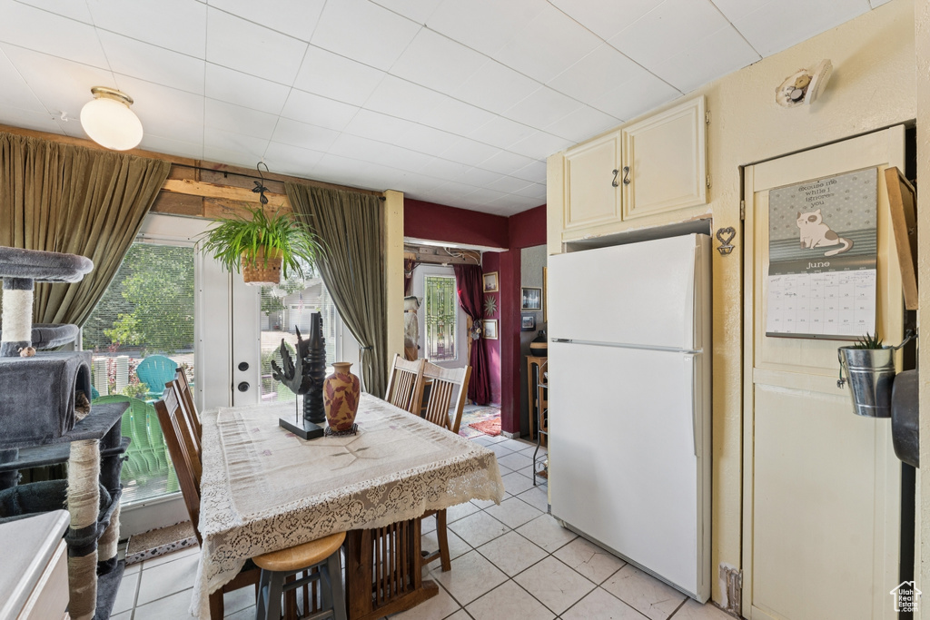 Kitchen with freestanding refrigerator, cream cabinets, and light tile patterned flooring
