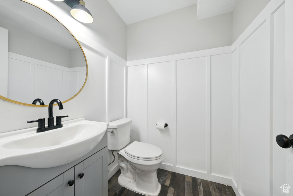 Bathroom with a decorative wall, vanity, wood finished floors, and a wainscoted wall