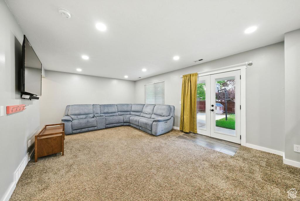 Carpeted living room with recessed lighting and french doors