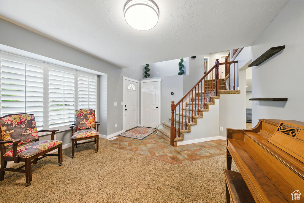 Carpeted foyer featuring stairway and baseboards