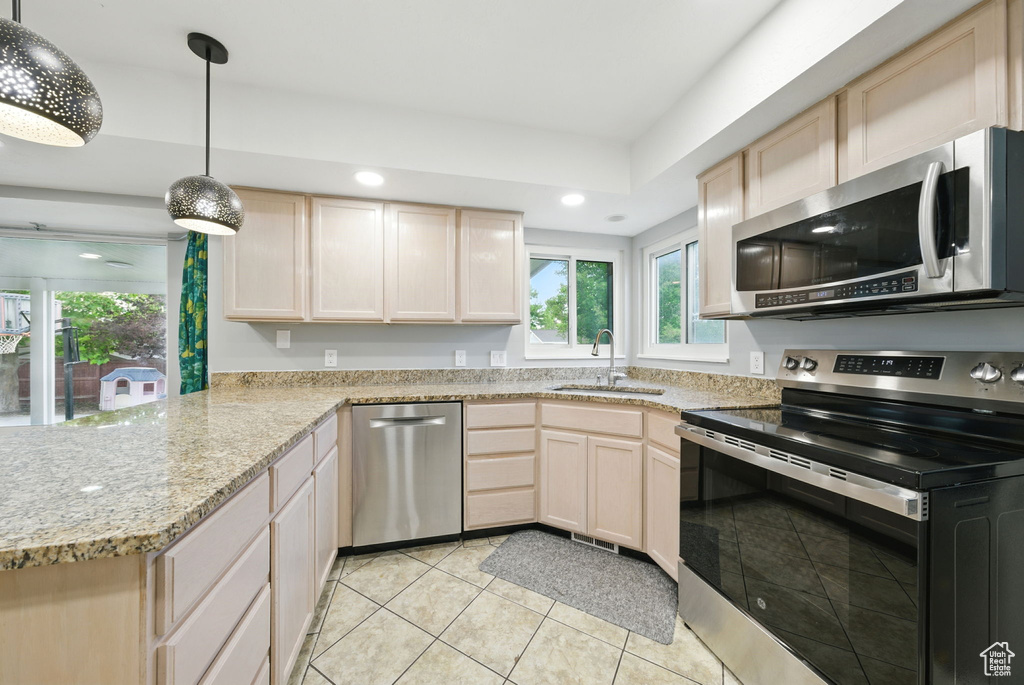 Kitchen with stainless steel appliances, light brown cabinetry, healthy amount of natural light, and recessed lighting
