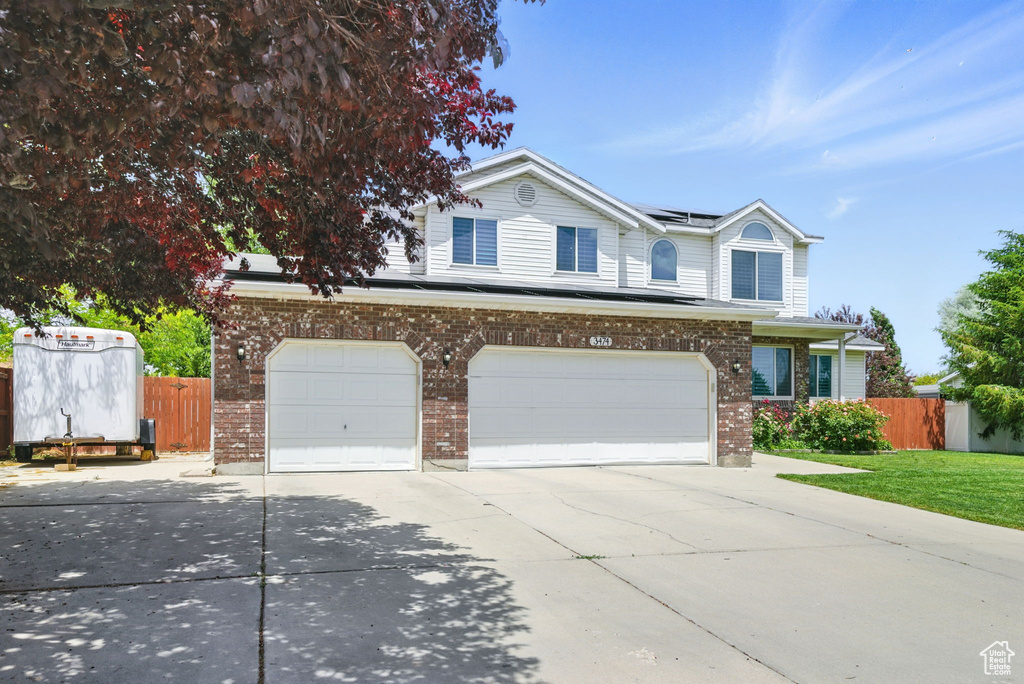 Traditional-style home with concrete driveway, a garage, solar panels, and brick siding