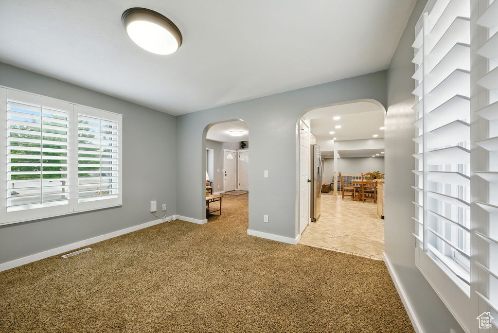 Empty room with arched walkways and light carpet